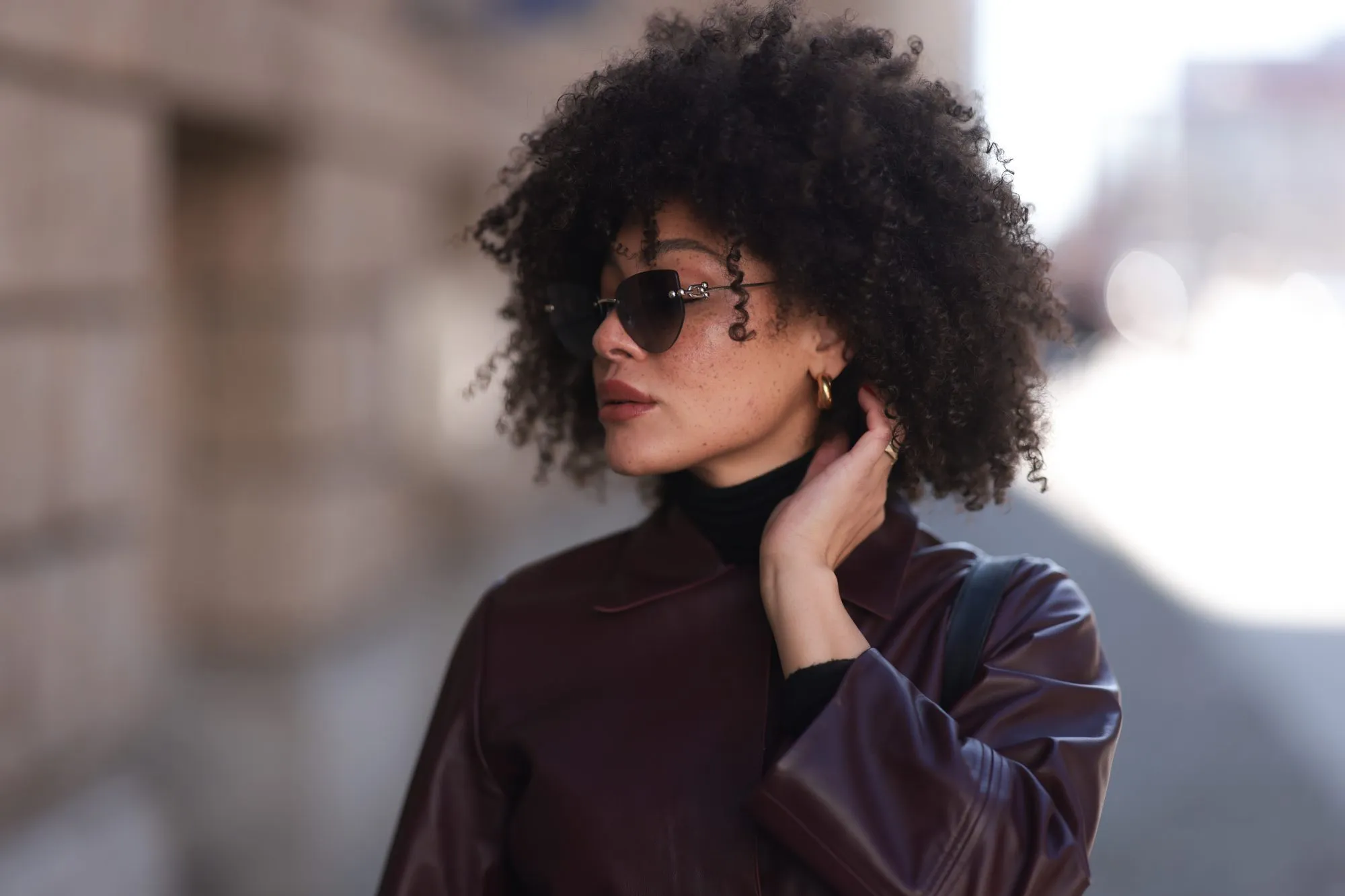 BERLIN, GERMANY - FEBRUARY 25: Julia Dalia seen wearing Tiffany & Co silver sunglasses, gold earrings, Arket black wool knit high neck sweater, burgundy red leather cropped jacket, on February 25, 2024 in Berlin, Germany. (Photo by Jeremy Moeller/Getty Images)