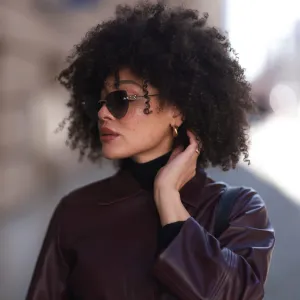 BERLIN, GERMANY - FEBRUARY 25: Julia Dalia seen wearing Tiffany & Co silver sunglasses, gold earrings, Arket black wool knit high neck sweater, burgundy red leather cropped jacket, on February 25, 2024 in Berlin, Germany. (Photo by Jeremy Moeller/Getty Images)