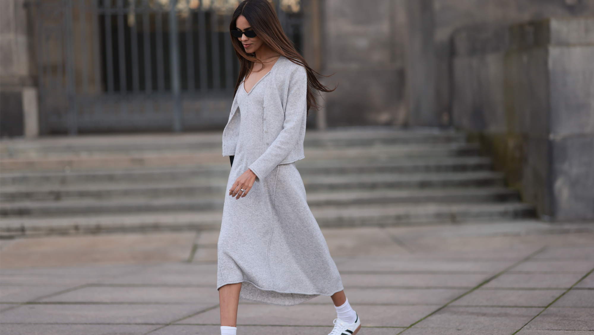 Jill Asemota seen wearing black vintage sunglasses, Dorothee Schumacher grey wool knit long dress, matching Dorothee Schumacher grey wool knit cardigan jacket, white cotton socks, Adidas white leather Samba sneakers, on November 04, 2023 in Berlin, Germany.