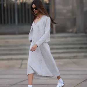Jill Asemota seen wearing black vintage sunglasses, Dorothee Schumacher grey wool knit long dress, matching Dorothee Schumacher grey wool knit cardigan jacket, white cotton socks, Adidas white leather Samba sneakers, on November 04, 2023 in Berlin, Germany.