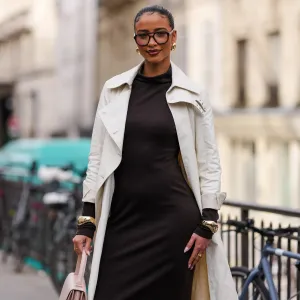 PARIS, FRANCE - MARCH 09: Flora Coquerel wears black sunglasses, gold earrings, dark brown high neck long sleeve midi dress, cream trench coat, gold bracelets, outside Akris, during the Paris Fashion week Women's Fall/Winter 2025-2026 on March 9, 2025 in Paris, France. (Photo by Edward Berthelot/Getty Images)