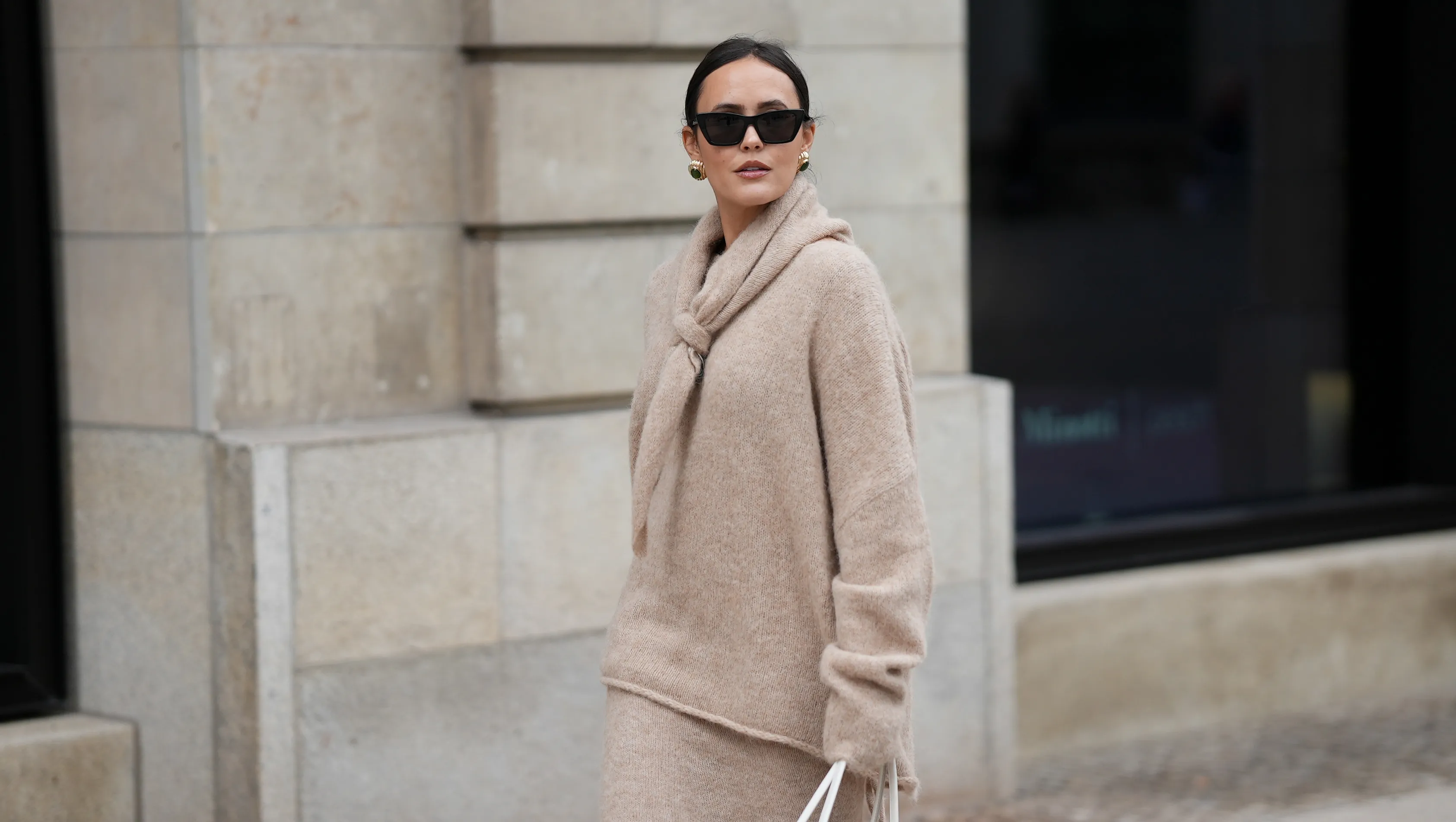 HAMBURG, GERMANY - OCTOBER 16: Laura Noltemeyer is seen wearing an oversized beige alpaca wool sweater with tie-back detailing by Aylin K&radic;&part;nig; a long alpaca wool knit skirt in a straight cut by Aylin K&radic;&part;nig; an alpaca knit scarf draped and knotted around the neck by Aylin K&radic;&part;nig; a white intrecciato leather handbag called &sbquo;&Auml;&ucirc;Arco Bag&sbquo;&Auml;&uacute; by Bottega Veneta; slim black cat-eye sunglasses by Yves Saint Laurent; gold statement earrings with a green stone detail by Mango; her brown and straight hair is tied in a low ponytail on October 16, 2025 in Hamburg, Germany. (Photo by Moritz Scholz/Getty Images)