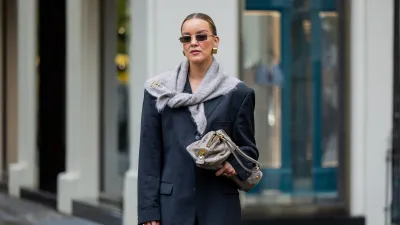 BERLIN, GERMANY - OCTOBER 08: Tina Haase wears vintage black oversize blazer, Black stirrup leggings, taupe knit triangle scarf Massimo Dutti, Loewe brooch, taupe grey Prada Bag on October 08, 2025 in Berlin, Germany. (Photo by Christian Vierig/Getty Images)