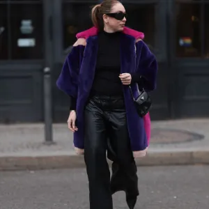 BERLIN, GERMANY - FEBRUARY 08: Sonia Lyson seen wearing & Other Stories black sunglasses, silver earrings, black wool knit high neck sweater, Marina Hoermanseder pink, purple, white, beige fake fur hooded short coat, Marc Cain black leather wide leg pants, Prada Cleo black leather mini bag and Jimmy Choo leather heeled boots, on February 08, 2024 in Berlin, Germany.