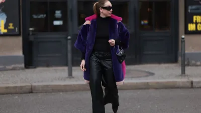 BERLIN, GERMANY - FEBRUARY 08: Sonia Lyson seen wearing & Other Stories black sunglasses, silver earrings, black wool knit high neck sweater, Marina Hoermanseder pink, purple, white, beige fake fur hooded short coat, Marc Cain black leather wide leg pants, Prada Cleo black leather mini bag and Jimmy Choo leather heeled boots, on February 08, 2024 in Berlin, Germany.