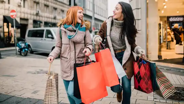 Happy two girls holding bunch of shopping bags