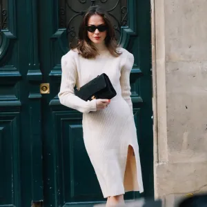Therese Hellström wears sunglasses, a white wool turtleneck slit dress with shoulder pads, a Chanel bag, black pointy shoes, on November 19, 2020 in Paris, France.
