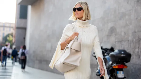 Linda Tol outside Max Mara fashion show wearing a knitted white dress, oversized white bag and sunglasses during the Milan Fashion Week - Spring / Summer 2022 on September 22, 2022 in Milan, Italy.