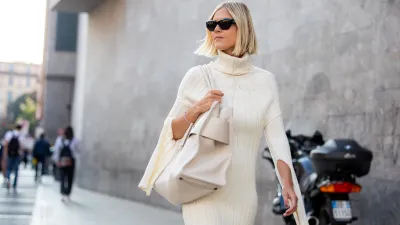 Linda Tol outside Max Mara fashion show wearing a knitted white dress, oversized white bag and sunglasses during the Milan Fashion Week - Spring / Summer 2022 on September 22, 2022 in Milan, Italy.