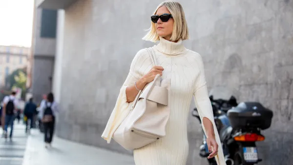 Linda Tol outside Max Mara fashion show wearing a knitted white dress, oversized white bag and sunglasses during the Milan Fashion Week - Spring / Summer 2022 on September 22, 2022 in Milan, Italy.