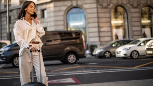 A happy pretty woman is walking on the street of Barcelona and enjoying a nice autumn day in the big city.
