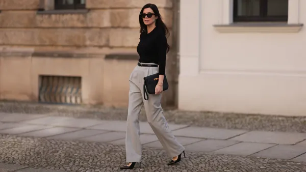 Leo Eberlin seen wearing Bottega Veneta black sunglasses, Leo Mathild jewelry / diamond bracelet and rings, Allude x Leo Mathild cashmere wool knit buttoned body, Toteme black leather belt, Velaa light grey elegant suit pants, Hermès black leather clutch bag and Saint Laurent black varnished leather heels / pumps, on February 25, 2024 in Berlin, Germany.