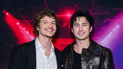 Connor Storrie and Hudson Williams smiling together at the "Heated Rivalry" season 1 premiere in Toronto.