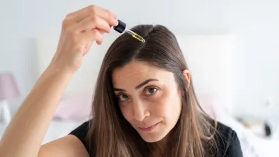 Woman Applying Hair Serum To Her Hair