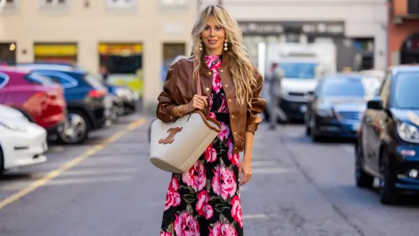 MILAN, ITALY - SEPTEMBER 25: Ekaterina Mamaeva wears dress with floral print Rotate, brown college leather jacket Celine, black boots Acne Studios, creme white brown bag Celine, earrings Cult Gaia during the Milan Fashion Week - Womenswear Spring/Summer 2024 on September 25, 2023 in Milan, Italy. (Photo by Christian Vierig/Getty Images)