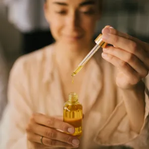 Portrait of beautiful young woman holding natural face oil. Beauty cosmetic concept.