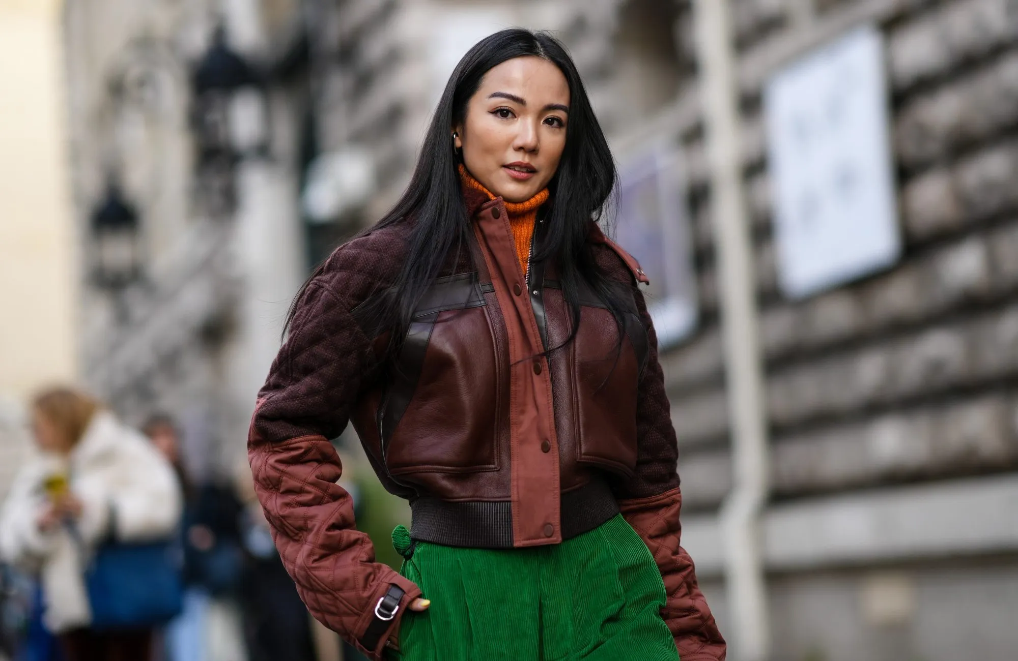 PARIS, FRANCE - MARCH 05: Yoyo Cao wears an orange ribbed wool turtleneck pullover, a brown shiny leather / black leather straps / quilted sleeves zipper jacket, green large ribbed velvet large pants, outside Hermes , during Paris Fashion Week - Womenswear F/W 2022-2023, on March 05, 2022 in Paris, France. (Photo by Edward Berthelot/Getty Images)