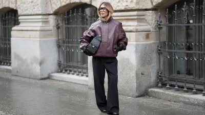 MUNICH, GERMANY - JANUARY 10: Oeznur Sinani alias Sinperi is seen wearing an oversized burgundy faux leather Prescott biker jacket with collar, hidden button front closure and minimalist design from The Frankie Shop; wide-leg black tailored trousers with relaxed fit from COS; black leather Tabi boots with flat sole and split toe from Maison Margiela; a black quilted grained calfskin leather Chanel 25 medium handbag with flap pockets, drawstring closing and golden chain strap and logo detail from Chanel; long black leather gloves from Mango; black oversized aviator glasses with black acetate frames and clear glasses from Prada; her blonde hair is styled in a blow out look on January 10, 2026 in Munich, Germany. (Photo by Moritz Scholz/Getty Images)
