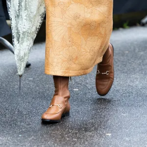 MILAN, ITALY - FEBRUARY 25: Jenny Walton wears beige leather Gucci boots, a green suede Gucci Horsebit bag, grey pendant earrings and a three-pieces brown leather and beige fabrics coord set made of a cropped top, a cropped jacket and a high waist midi skirt outside Gucci show during the Milan Fashion Week Womenswear Fall/Winter 2025/2026 on February 25, 2025 in Milan, Italy. (Photo by Valentina Frugiuele/Getty Images)