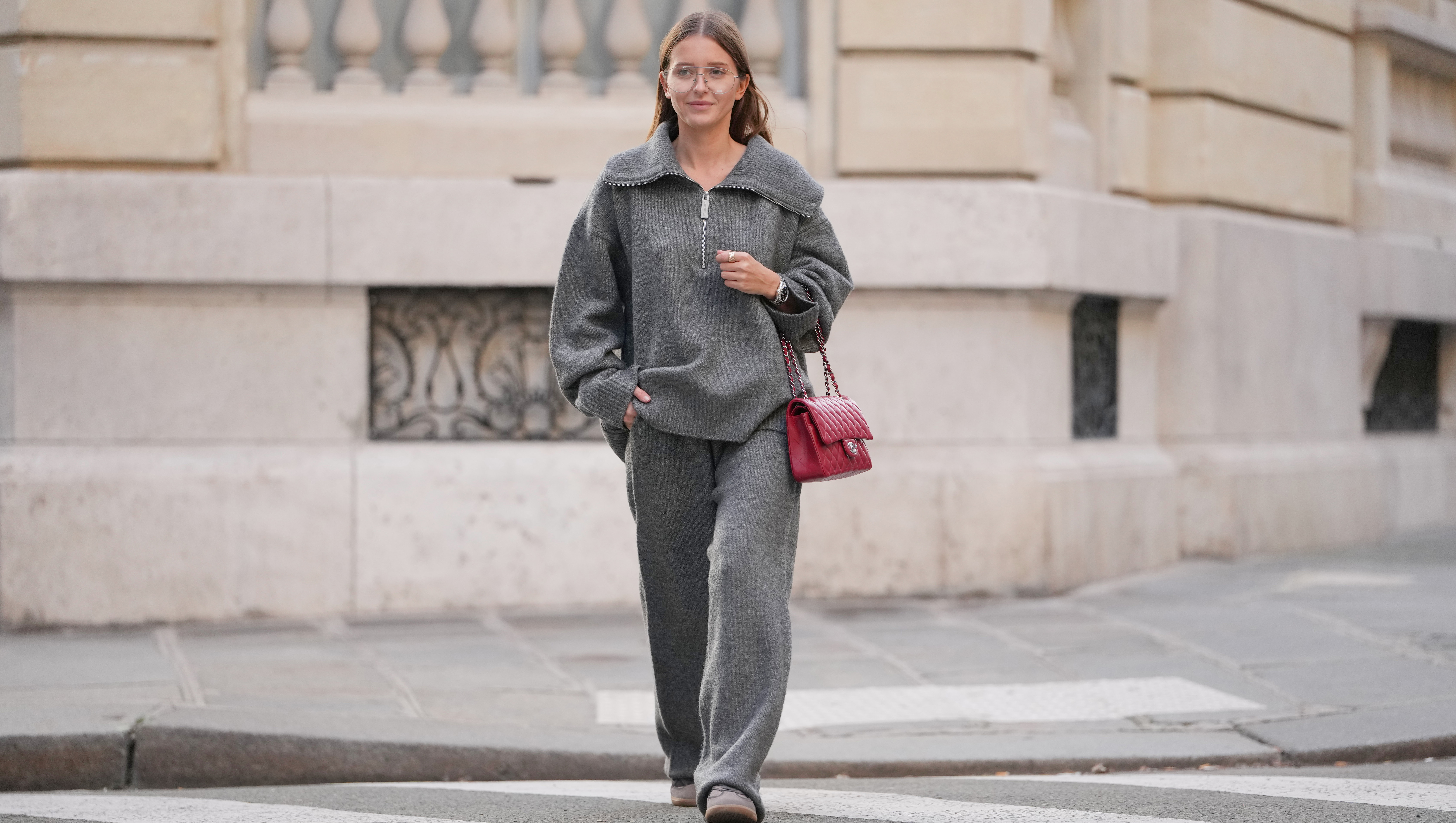 PARIS, FRANCE - DECEMBER 18: Diane Batoukina wears a grey wool zip-up top by WRSTBHVR Worst Behavior with a wide funnel collar, dropped shoulders, long sleeves and a relaxed fit, matching grey wool wide-leg pants with an elasticated waist by WRSTBHVR Worst Behavior, clear eyeglasses with thin frames, a red quilted leather Chanel flap bag with silver-tone chain strap, brown suede lace-up shoes by Alohas with rubber soles, during a street style fashion photo session, on December 18, 2025 in Paris, France. (Photo by Edward Berthelot/Getty Images)