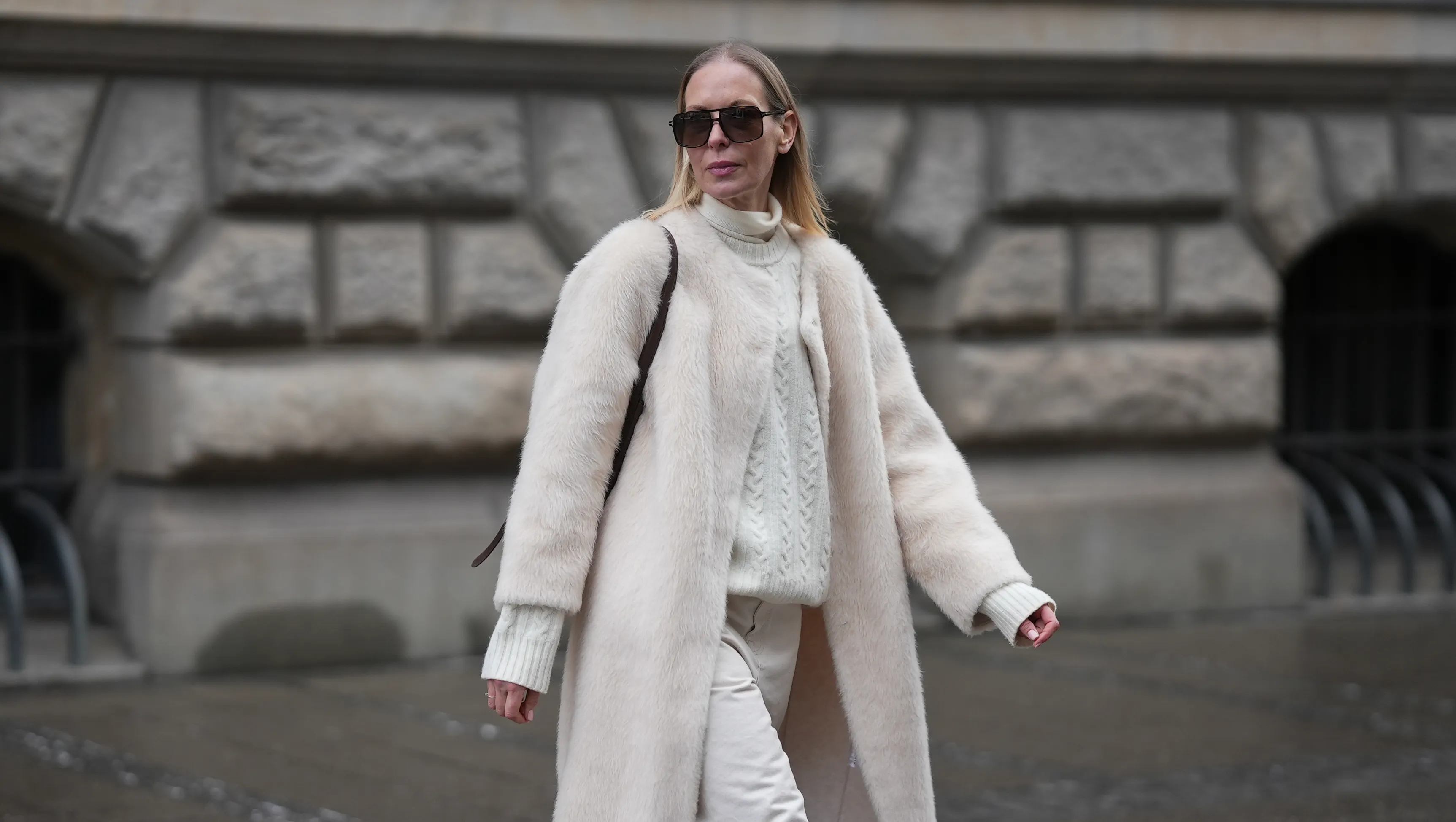 MUNICH, GERMANY - JANUARY 8: Mirja Klein is seen wearing a &sbquo;&Auml;&uacute;Nora brushed wool coat&sbquo;&Auml;&ugrave; in a cloud dancer tone with a straight silhouette, clean open front and subtle texture from Marcella London; a cream turtleneck knit sweater with a cable knit pattern, high ribbed collar and fitted cuffs in a cloud dancer shade from Massimo Dutti; off white straight leg Jeans with a high rise and structured cotton fabric from R&radic;&ge;he Frames; a brown belted bucket bag in smooth leather with a structured silhouette and top handle from Le Liffner; oversized rectangular sunglasses with a thin acetate frame, double bridge and tinted lenses from Tom Ford; her long blond straight hair is worn loose and parted in the middle on January 8, 2026 in Munich, Germany. (Photo by Moritz Scholz/Getty Images)