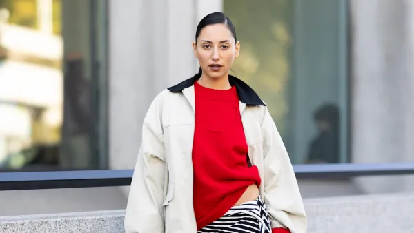 PARIS, FRANCE - OCTOBER 07: A guest wears a red sweater, a black and white striped asymmetrical skirt, gold heeled sandals and a beige and black jacket outside Christopher Esber show during the Womenswear Spring Summer 2026 as part of Paris Fashion Week on October 07, 2025 in Paris, France. (Photo by Valentina Frugiuele/Getty Images)