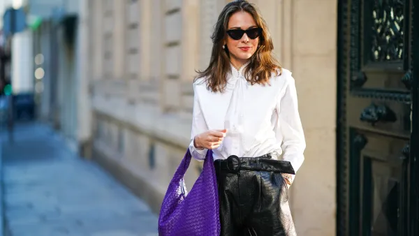 Therese Hellström wears a white shirt blouse from Tory Burch, black leather shorts from Custommade, a purple large woven leather bag from Bottega Veneta, sunglasses from Chimi Eyewear, on November 05, 2020 in Paris, France.