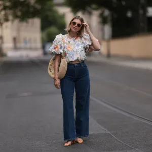 Aline Kaplan wearing Baum & Pferdgarten wide leg blue denim pants, & other stories white flower pattern cropped blouse and orange summer heels and Mango orange black shades on June 06, 2023 in Berlin, Germany.