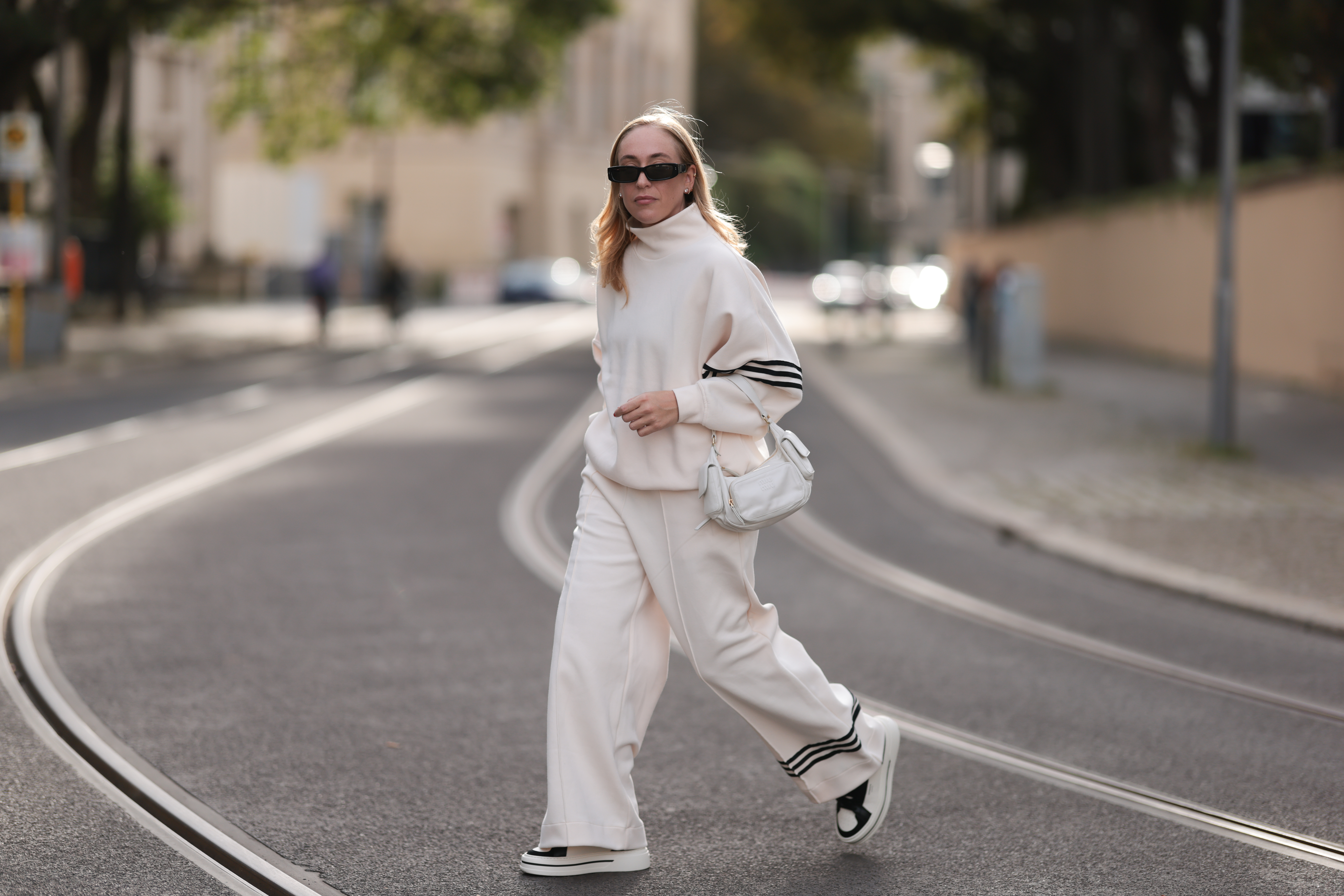 Sonia Lyson seen wearing Linda Farrow black sunglasses, Adidas white two-piece / white logo cotton oversized sweater and matching white wide leg pants, Miu Miu white leather Pocket bag, Copenhagen Studios white with black details leather sneakers, on September 03, 2023 in Berlin, Germany.