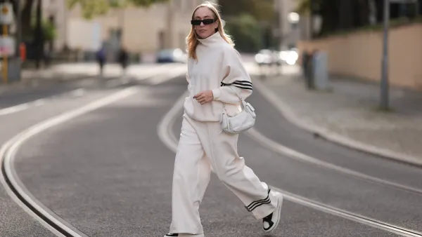 Sonia Lyson seen wearing Linda Farrow black sunglasses, Adidas white two-piece / white logo cotton oversized sweater and matching white wide leg pants, Miu Miu white leather Pocket bag, Copenhagen Studios white with black details leather sneakers, on September 03, 2023 in Berlin, Germany.
