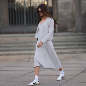 Jill Asemota seen wearing black vintage sunglasses, Dorothee Schumacher grey wool knit long dress, matching Dorothee Schumacher grey wool knit cardigan jacket, white cotton socks, Adidas white leather Samba sneakers, on November 04, 2023 in Berlin, Germany.