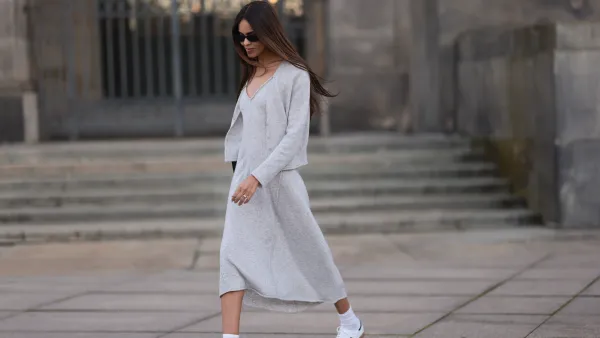 Jill Asemota seen wearing black vintage sunglasses, Dorothee Schumacher grey wool knit long dress, matching Dorothee Schumacher grey wool knit cardigan jacket, white cotton socks, Adidas white leather Samba sneakers, on November 04, 2023 in Berlin, Germany.