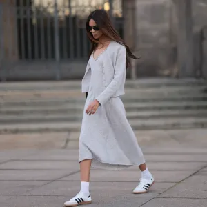 Jill Asemota seen wearing black vintage sunglasses, Dorothee Schumacher grey wool knit long dress, matching Dorothee Schumacher grey wool knit cardigan jacket, white cotton socks, Adidas white leather Samba sneakers, on November 04, 2023 in Berlin, Germany.