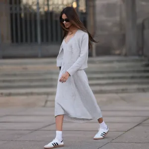 Jill Asemota seen wearing black vintage sunglasses, Dorothee Schumacher grey wool knit long dress, matching Dorothee Schumacher grey wool knit cardigan jacket, white cotton socks, Adidas white leather Samba sneakers, on November 04, 2023 in Berlin, Germany.