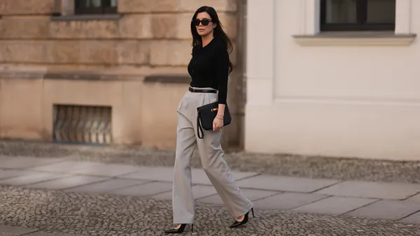 Leo Eberlin seen wearing Bottega Veneta black sunglasses, Leo Mathild jewelry / diamond bracelet and rings, Allude x Leo Mathild cashmere wool knit buttoned body, Toteme black leather belt, Velaa light grey elegant suit pants, Hermès black leather clutch bag and Saint Laurent black varnished leather heels / pumps, on February 25, 2024 in Berlin, Germany.