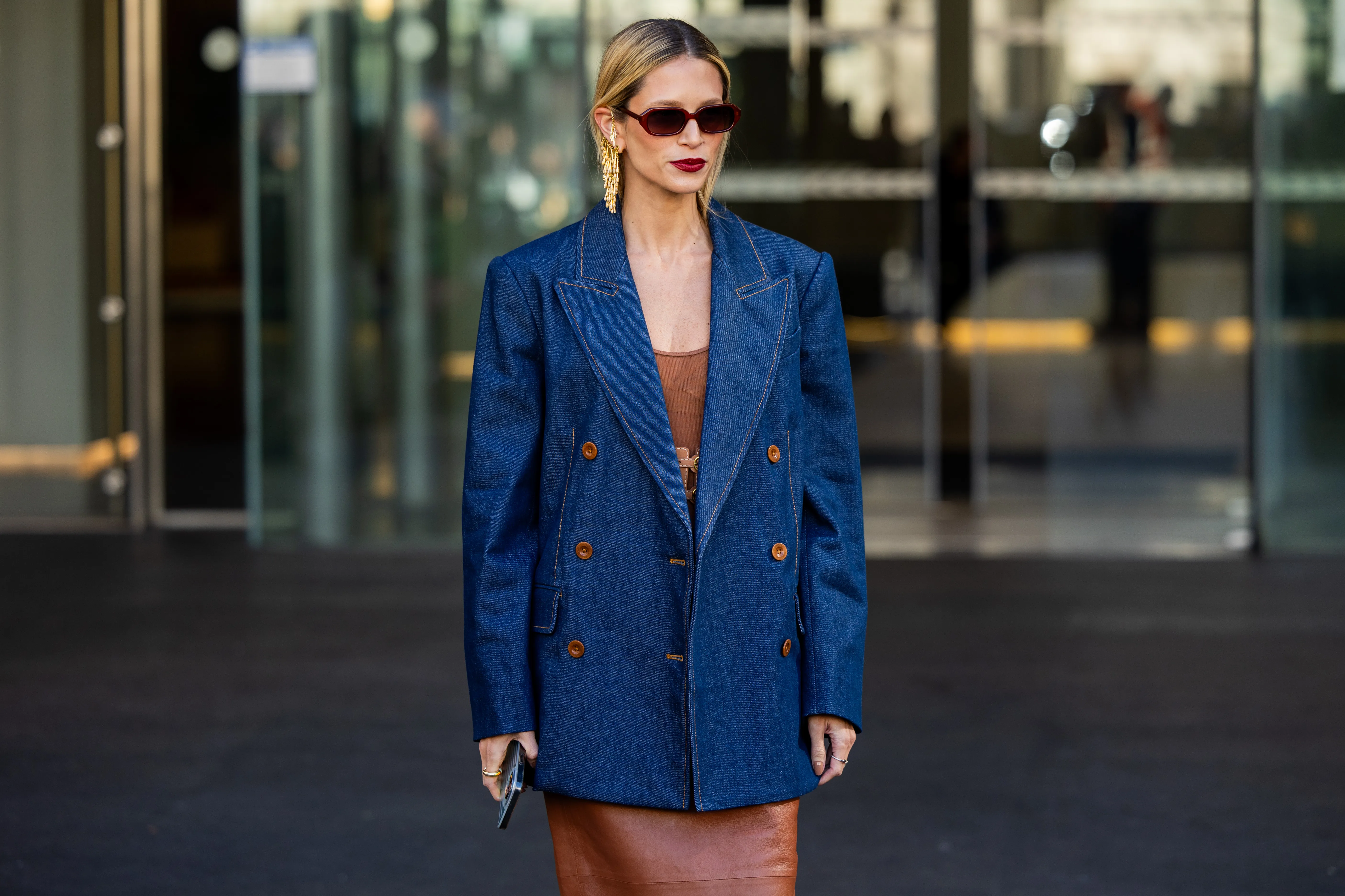 Helena Bordon wears denim blazer, brown dress, sunglasses, golden earrings outside Zimmermann during the Womenswear Fall/Winter 2024/2025 as part of Paris Fashion Week on March 04, 2024 in Paris, France.