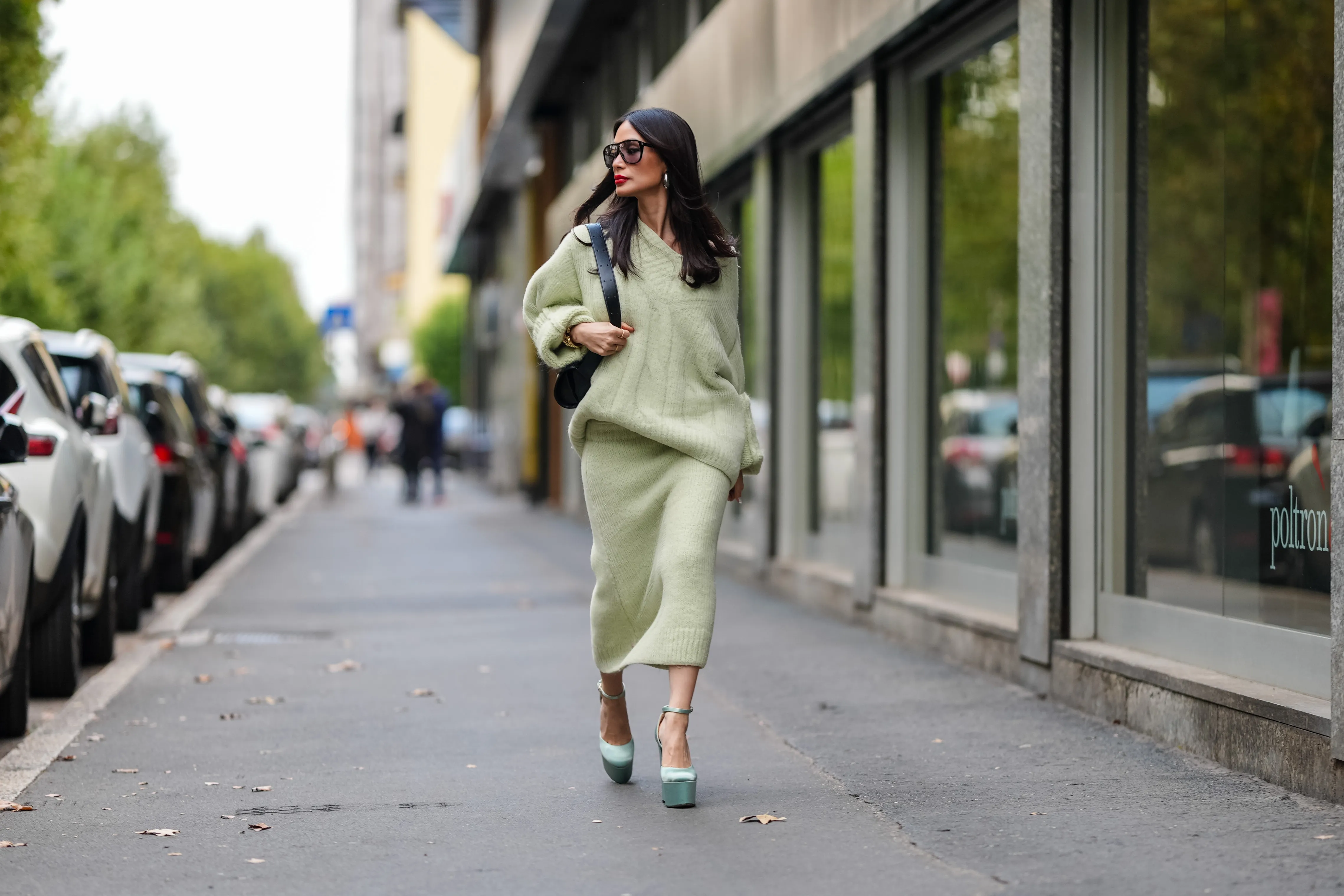 MILAN, ITALY - SEPTEMBER 18: Heart Evangelista wears silver earrings, light green oversized Jil Sander sweater, shiny black leather bag, black sunglasses, a white gold diamond ring, gold bracelets, light green Jil Sander sweater midi skirt, light blue satin platform heels with strap, outside Jil Sander, during the Milan Fashion Week Spring/Summer 2024-2025 on September 18, 2024 in Milan, Italy. (Photo by Edward Berthelot/Getty Images)