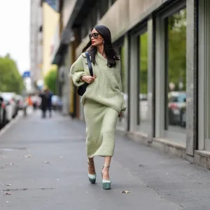 MILAN, ITALY - SEPTEMBER 18: Heart Evangelista wears silver earrings, light green oversized Jil Sander sweater, shiny black leather bag, black sunglasses, a white gold diamond ring, gold bracelets, light green Jil Sander sweater midi skirt, light blue satin platform heels with strap, outside Jil Sander, during the Milan Fashion Week Spring/Summer 2024-2025 on September 18, 2024 in Milan, Italy. (Photo by Edward Berthelot/Getty Images)