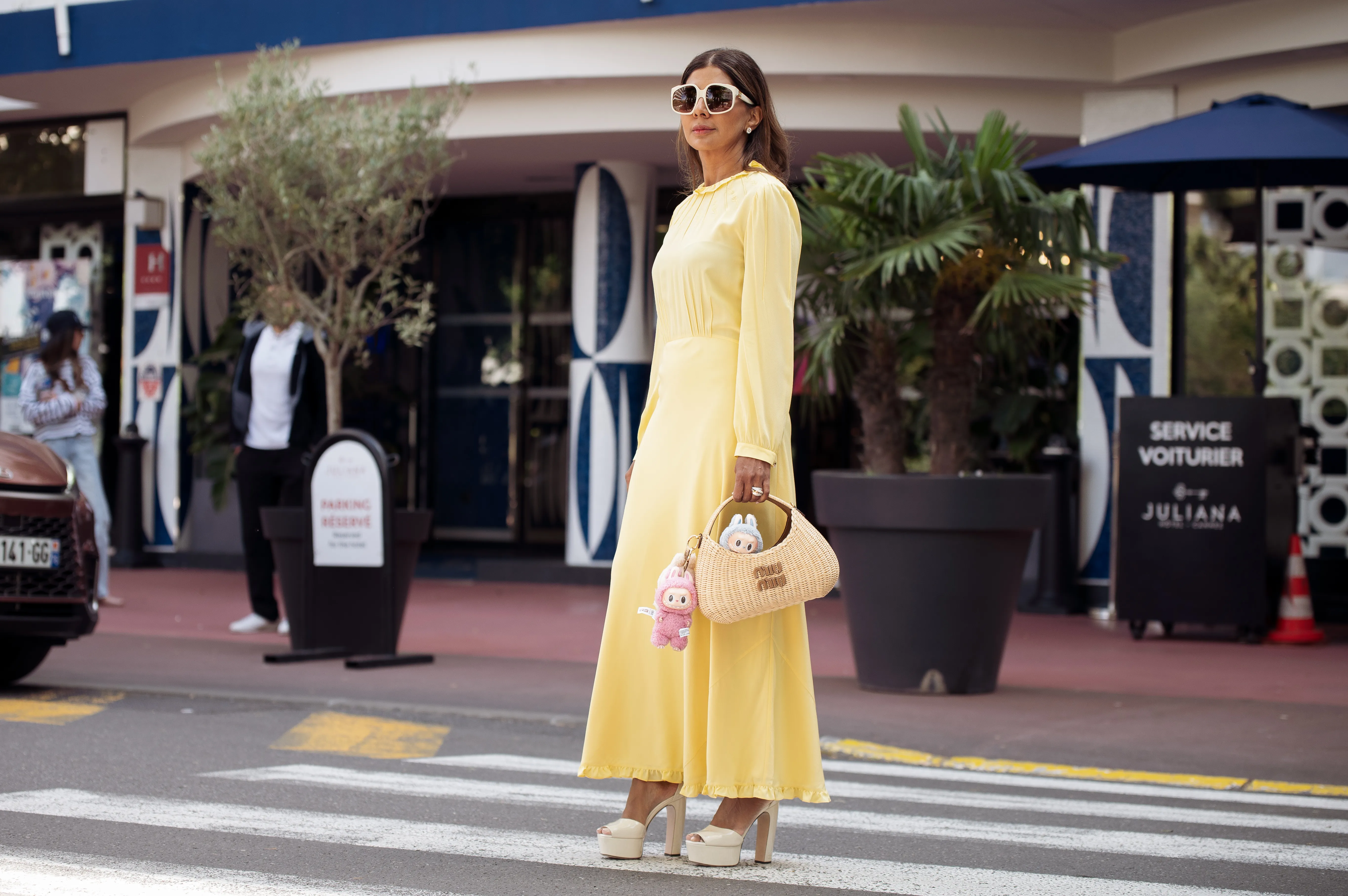 CANNES, FRANCE - MAY 17: Zufi Alexander wears an all Miu Miu look made of butter yellow long summer dress, off white pumps high heels with platform, sunglasses and straw Miu Miu bag with attached Labubu bag charms during day five of the 78th Cannes Film Festival on May 17, 2025 in Cannes, France. (Photo by Raimonda Kulikauskiene/Getty Images)