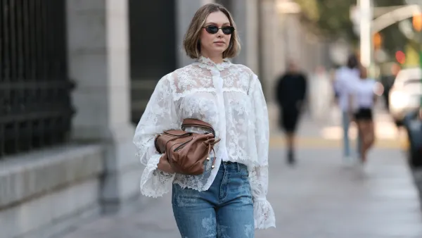 NEW YORK, NEW YORK - SEPTEMBER 14: Kate Smolianinova seen wearing Vehla Eyewear slim rectangular sunglasses in a dark brown. Her hair styled in a sleek chin-length bob with a soft middle part. A Kobi Halperin sheer white lace blouse with floral embroidery, high ruffled collar, voluminous sleeves and scalloped edges, paired with Kobi Halperin blue high-waist flared jeans featuring tonal floral jacquard detailing and a Gerard Darel soft brown leather handbag with gathered pleats and rounded handles, outside the Ulla Johnson show, during New York Fashion Week, on September 14, 2025 in New York City. (Photo by Jeremy Moeller/Getty Images)