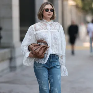 NEW YORK, NEW YORK - SEPTEMBER 14: Kate Smolianinova seen wearing Vehla Eyewear slim rectangular sunglasses in a dark brown. Her hair styled in a sleek chin-length bob with a soft middle part. A Kobi Halperin sheer white lace blouse with floral embroidery, high ruffled collar, voluminous sleeves and scalloped edges, paired with Kobi Halperin blue high-waist flared jeans featuring tonal floral jacquard detailing and a Gerard Darel soft brown leather handbag with gathered pleats and rounded handles, outside the Ulla Johnson show, during New York Fashion Week, on September 14, 2025 in New York City. (Photo by Jeremy Moeller/Getty Images)