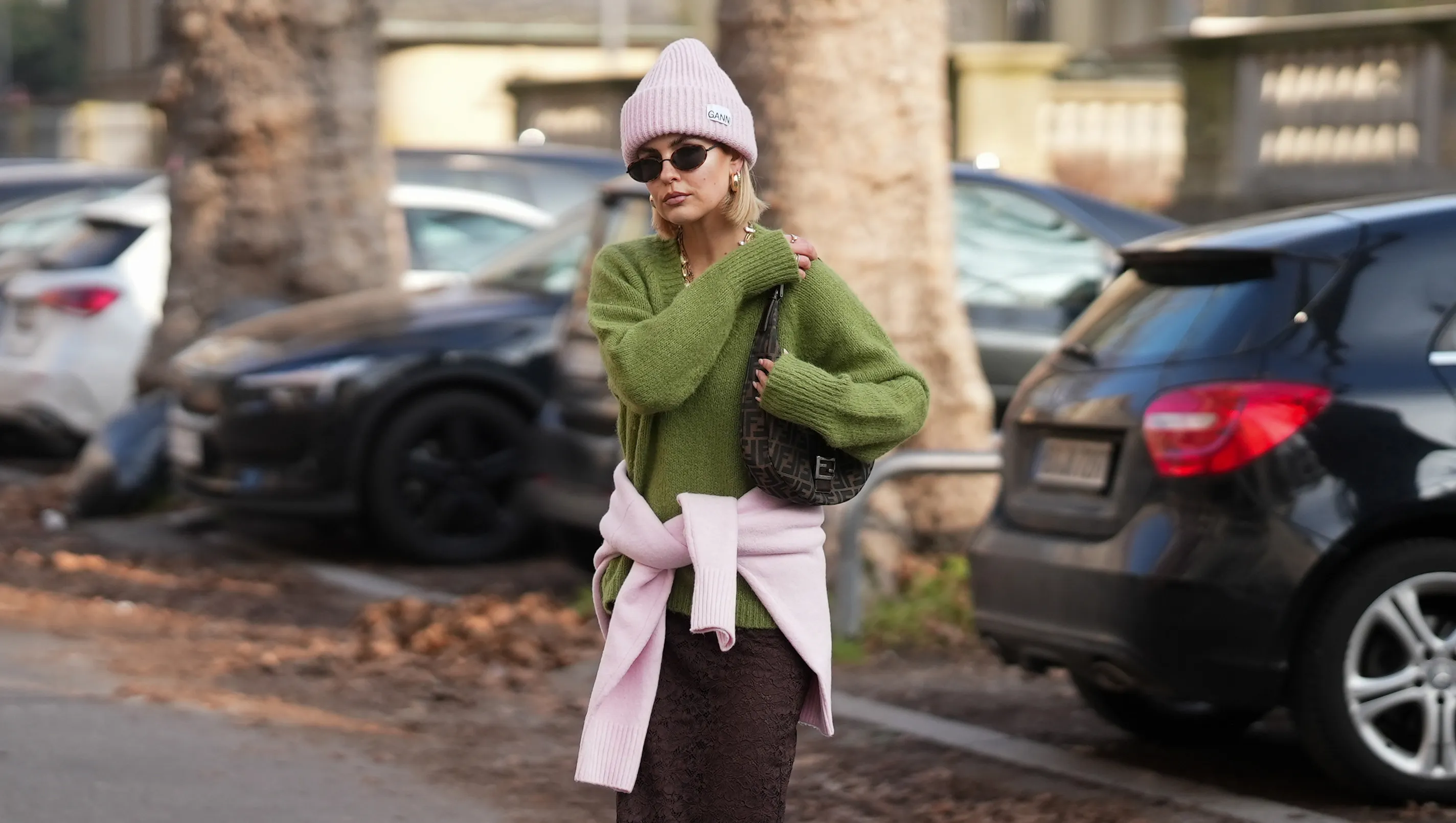 FRANKFURT AM MAIN, GERMANY - JANUARY 21: Julia Kammerer is seen wearing a light green V-neck knit sweater from COS; a pink knit sweater tied around the waist from Zara; a brown midi lace skirt with straight fit from H&M; a light pink beanie wool hat with white logo patch from Ganni; oval-shaped sunglasses with golden frames and tinted lenses from Vela; a brown Zucca croissant shoulder bag with monogram canvas, brown leather strap closure and silver logo buckle from Fendi; chunky golden hoop earrings from COS; brown leather biker boots with clasp and chunky silhouette from Even & Odd; her blonde hair styled in a sleek look under the hat on January 21, 2026 in Frankfurt am Main, Germany. (Photo by Moritz Scholz/Getty Images)