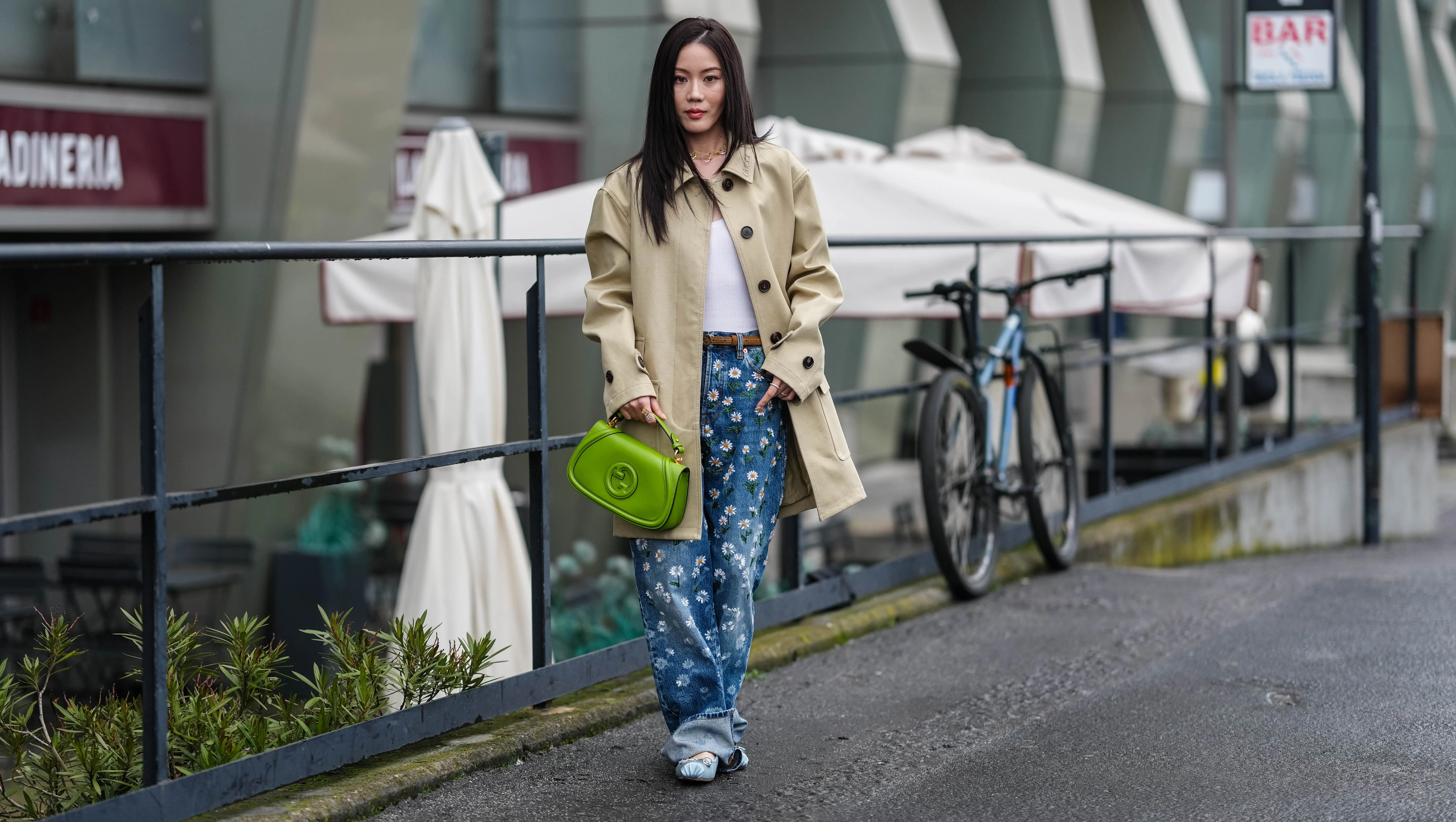 MILAN, ITALY - FEBRUARY 25: Jenny Tsang wears a white t-shirt, gold necklace, a cream oversized jacket, blue denim jeans / pants with floral details, a light brown leather belt, a green leather Gucci bag, light blue satin Gucci ballerinas shoes with gold details, outside Gucci, during the Milan Fashion Week Womenswear Fall/Winter 2025/2026 on February 25, 2025 in Milan, Italy. (Photo by Edward Berthelot/Getty Images)