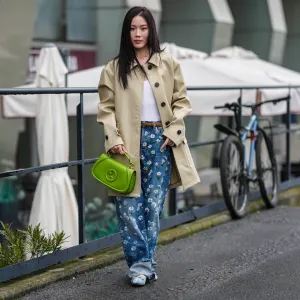 MILAN, ITALY - FEBRUARY 25: Jenny Tsang wears a white t-shirt, gold necklace, a cream oversized jacket, blue denim jeans / pants with floral details, a light brown leather belt, a green leather Gucci bag, light blue satin Gucci ballerinas shoes with gold details, outside Gucci, during the Milan Fashion Week Womenswear Fall/Winter 2025/2026 on February 25, 2025 in Milan, Italy. (Photo by Edward Berthelot/Getty Images)