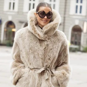 COPENHAGEN, DENMARK - JANUARY 29: Nina Sandbech wears a beige plush faux-fur belted jacket with a high funnel neck, matching beige sheer skirt with fur-trim hems, black glossy knee-high patent leather boots, oversized round black Prada sunglasses during Copenhagen Fashion Week AW26, is seen wearing on January 29, 2026 in Copenhagen, Denmark. (Photo by Raimonda Kulikauskiene/WireImage)