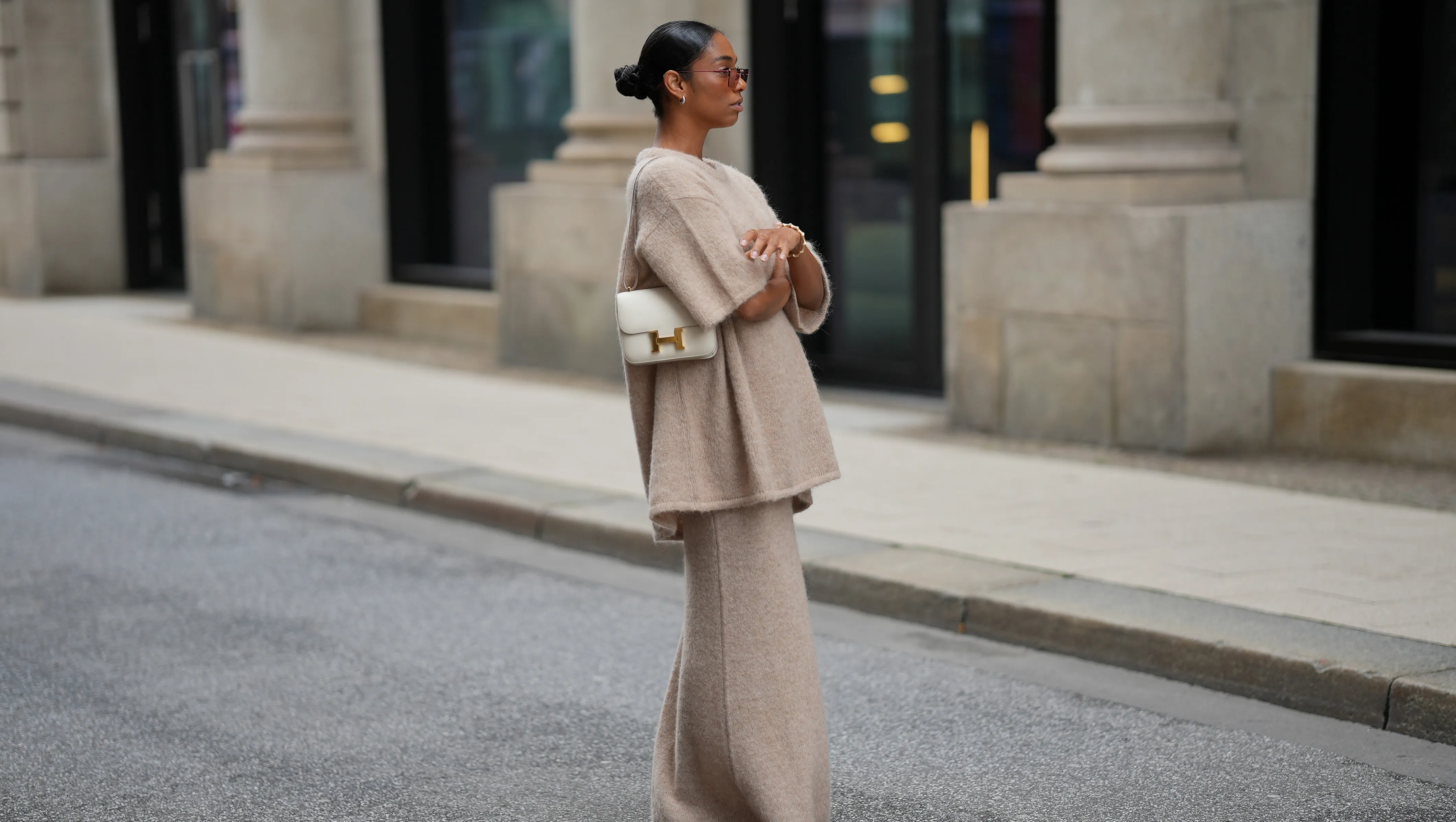 HAMBURG, GERMANY - SEPTEMBER 19: Cherifa Akili is seen wearing an oversized beige short-sleeve knit sweater with a soft texture from Byaylink&radic;&part;nig; a matching long knit skirt in a beige tone with subtle seaming at the hem from Byaylink&radic;&part;nig; red pointed-toe heels with a low cut from Prada; The Constance structured white leather shoulder bag with a gold clasp from Hermes; a gold spiral shaped bracelet from Elouise; two gold, metallic rings from Elouise, Wempe; lightly tinted sunglasses in a warm shade COS; her black hair is pulled back in a sleek bun on September 19, 2025 in Hamburg, Germany. (Photo by Moritz Scholz/Getty Images)