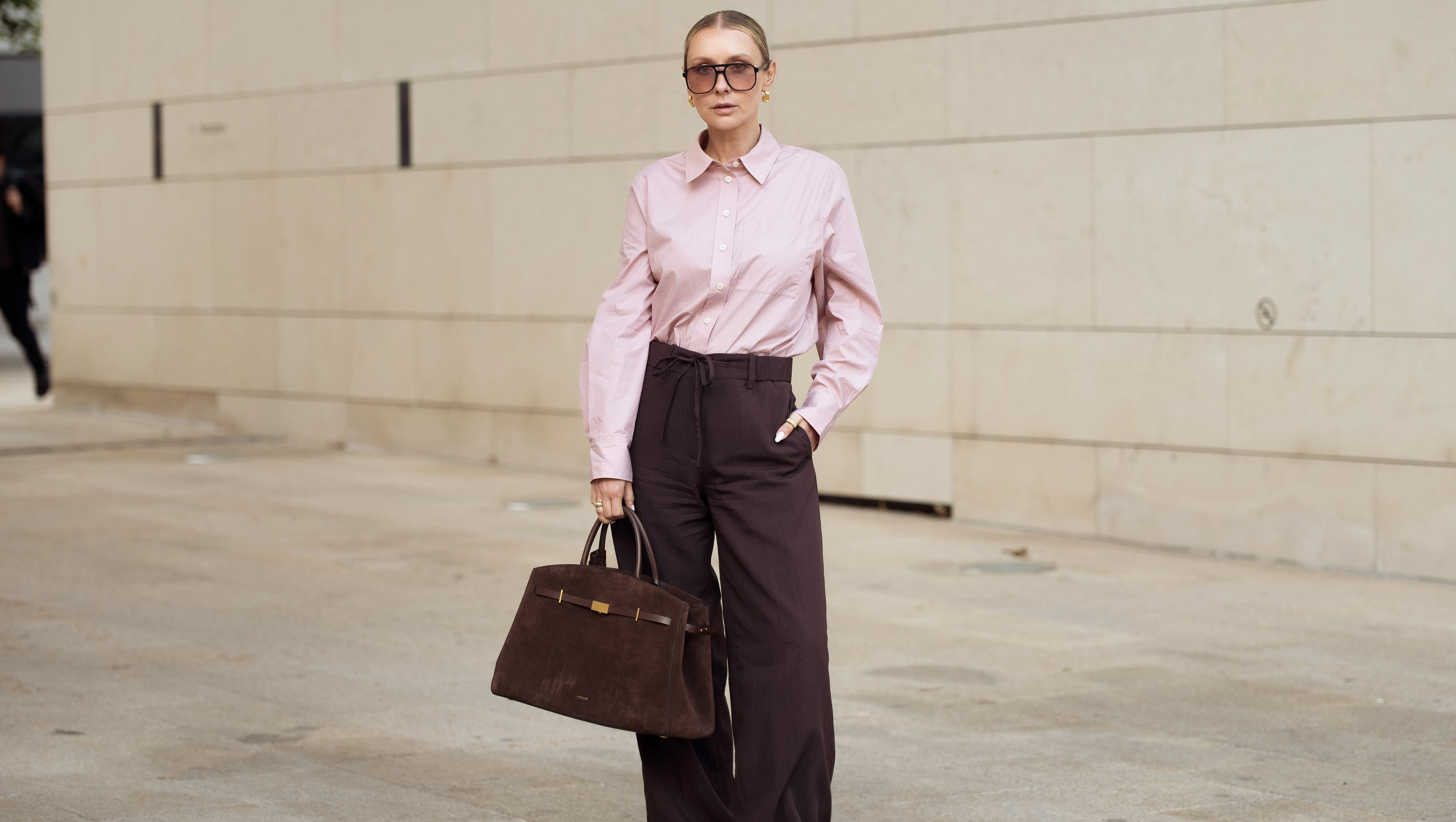 COPENHAGEN, DENMARK - AUGUST 05: Justyna Czerniak wears brown pants, pink shirt, sunglasses and brown suede bag during Copenhagen Fashion Week day two on August 05, 2025 in Copenhagen, Denmark. (Photo by Raimonda Kulikauskiene/Getty Images)