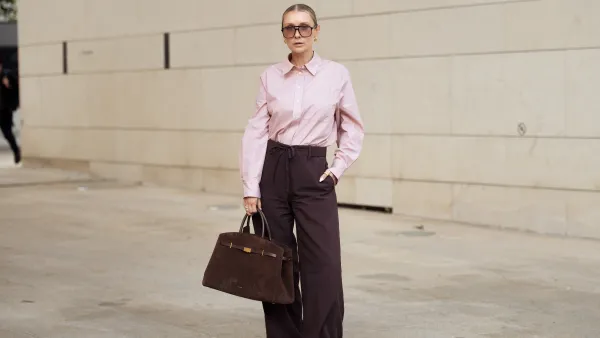 COPENHAGEN, DENMARK - AUGUST 05: Justyna Czerniak wears brown pants, pink shirt, sunglasses and brown suede bag during Copenhagen Fashion Week day two on August 05, 2025 in Copenhagen, Denmark. (Photo by Raimonda Kulikauskiene/Getty Images)