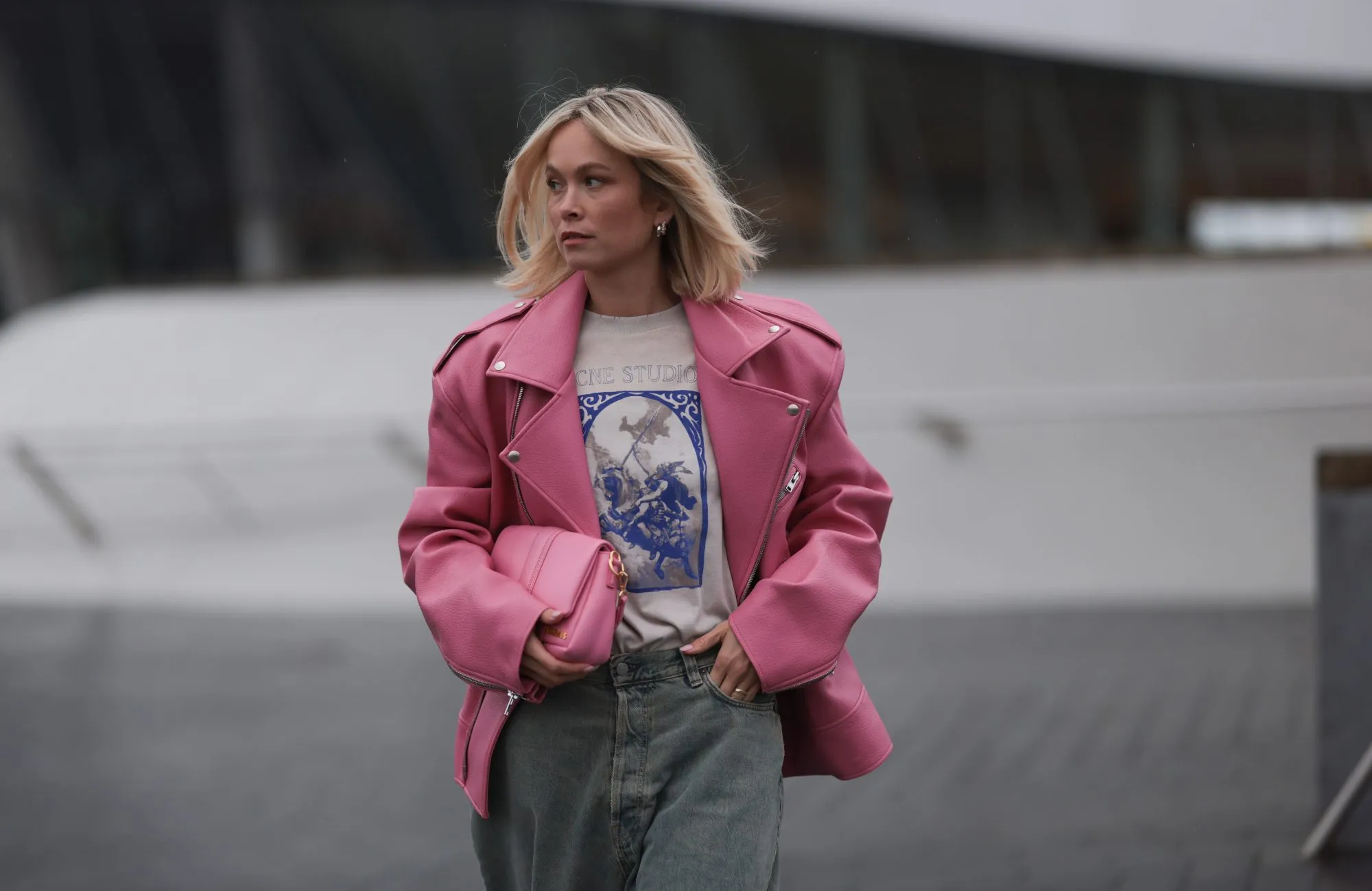 MUNICH, GERMANY - MARCH 06: Nadine Berneis seen wearing The Frankie Shop pink oversized leather jacket, Acne Studios off-white / blue print pattern graphic cotton t-shirt, Acne Studios light blue / grey denim wide leg jeans / pans and Jacquemus pink leather Bambimou bag, on March 06, 2024 in Munich, Germany. (Photo by Jeremy Moeller/Getty Images)