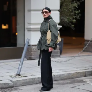 MUNICH, GERMANY - FEBRUARY 1: Sofiya Bogopolska Balci is seen wearing a calligraphy green jacket with a hip belt and buckles on the arms and balloon hems with silver buttons; dark grey wool jumper; straight-cut black fabric trousers from COS; black leather boots with rectangular toes from Ayede; dark brown aviator sunglasses from Prada, silver stud earrings from Cartier; gold and silver rings from Cartier; a silver Rolex; a pastel yellow Chanel 25 bag in caviar leather; her black hair is styled in sleek bun on February 1, 2026 in Munich, Germany. (Photo by Moritz Scholz/Getty Images)